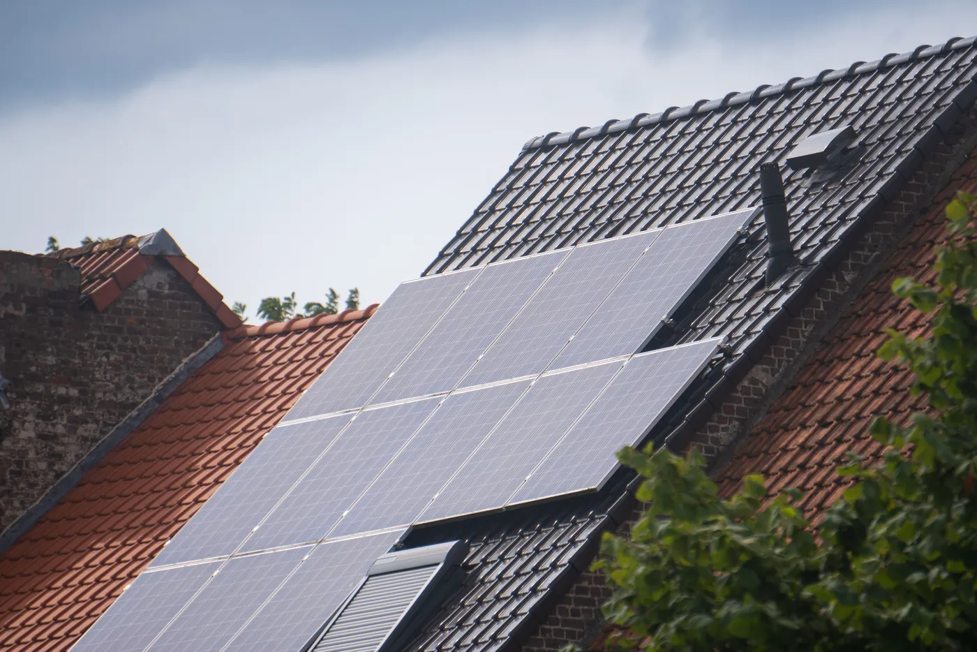 Photovoltaikmodule auf einem steilen dunklen Ziegeldach neben einem roten Nachbardach (Eggolsheim, Landkreis Forchheim)