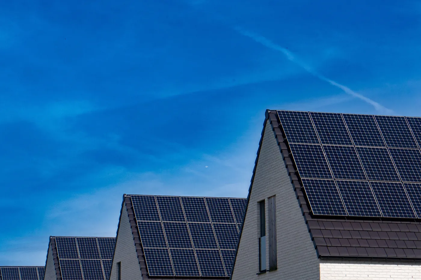 Giebeldächer moderner Einfamilienhäuser mit schwarzen Solarmodulen vor blauem Himmel (Rosdorf, Landkreis Göttingen)