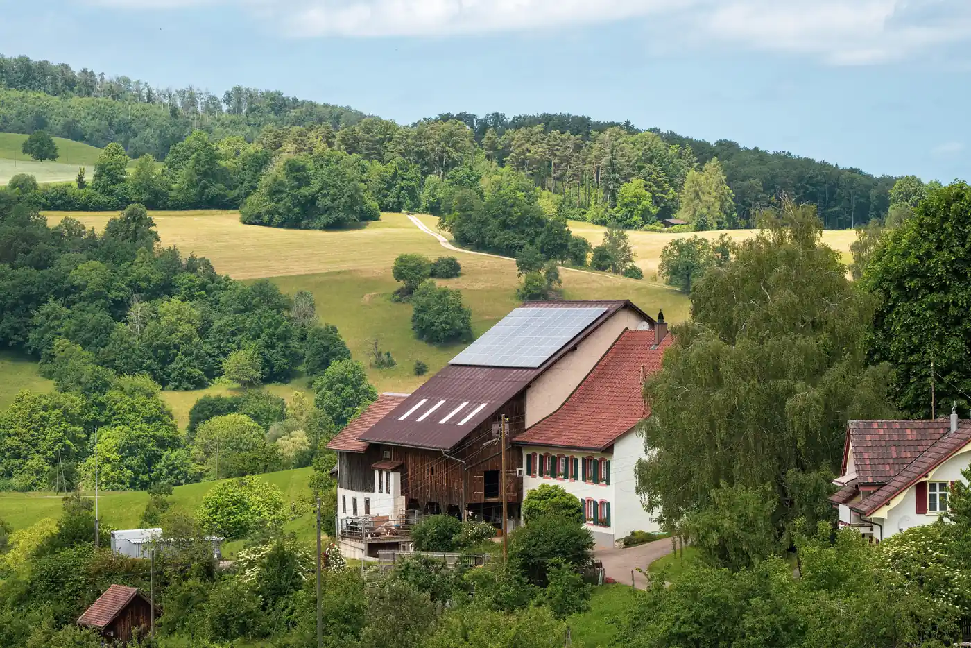 Bauernhaus mit Photovoltaikanlage auf dem Dach in einer grünen Hügellandschaft (Weiterstadt, Landkreis Darmstadt-Dieburg)