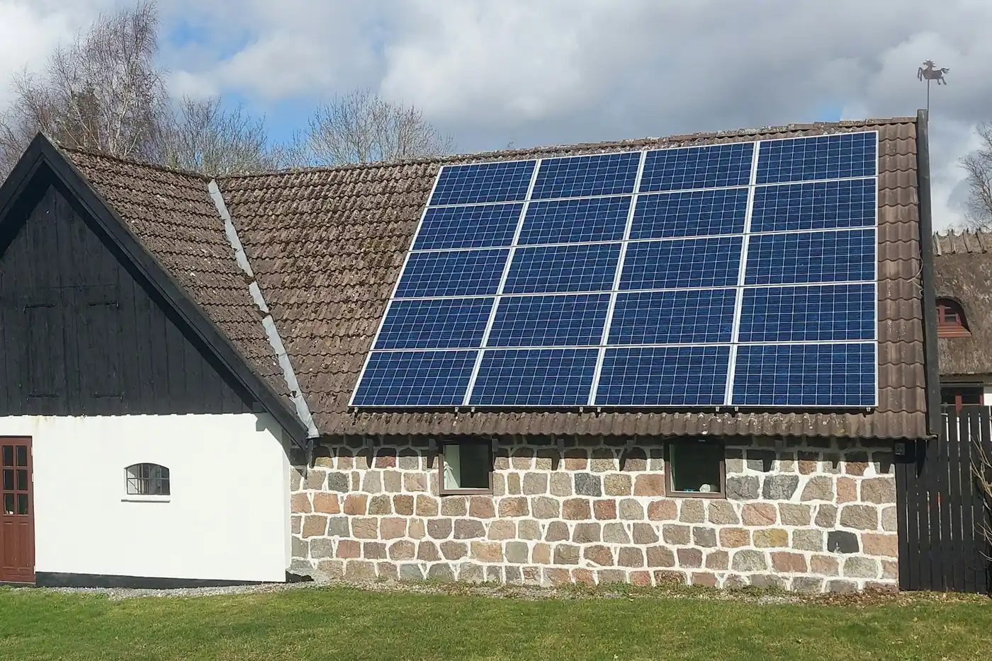 Altes Haus mit Feldsteinmauer und blauen Solarmodulen auf dem braunen Ziegeldach (Kölleda, Landkreis Sömmerda)