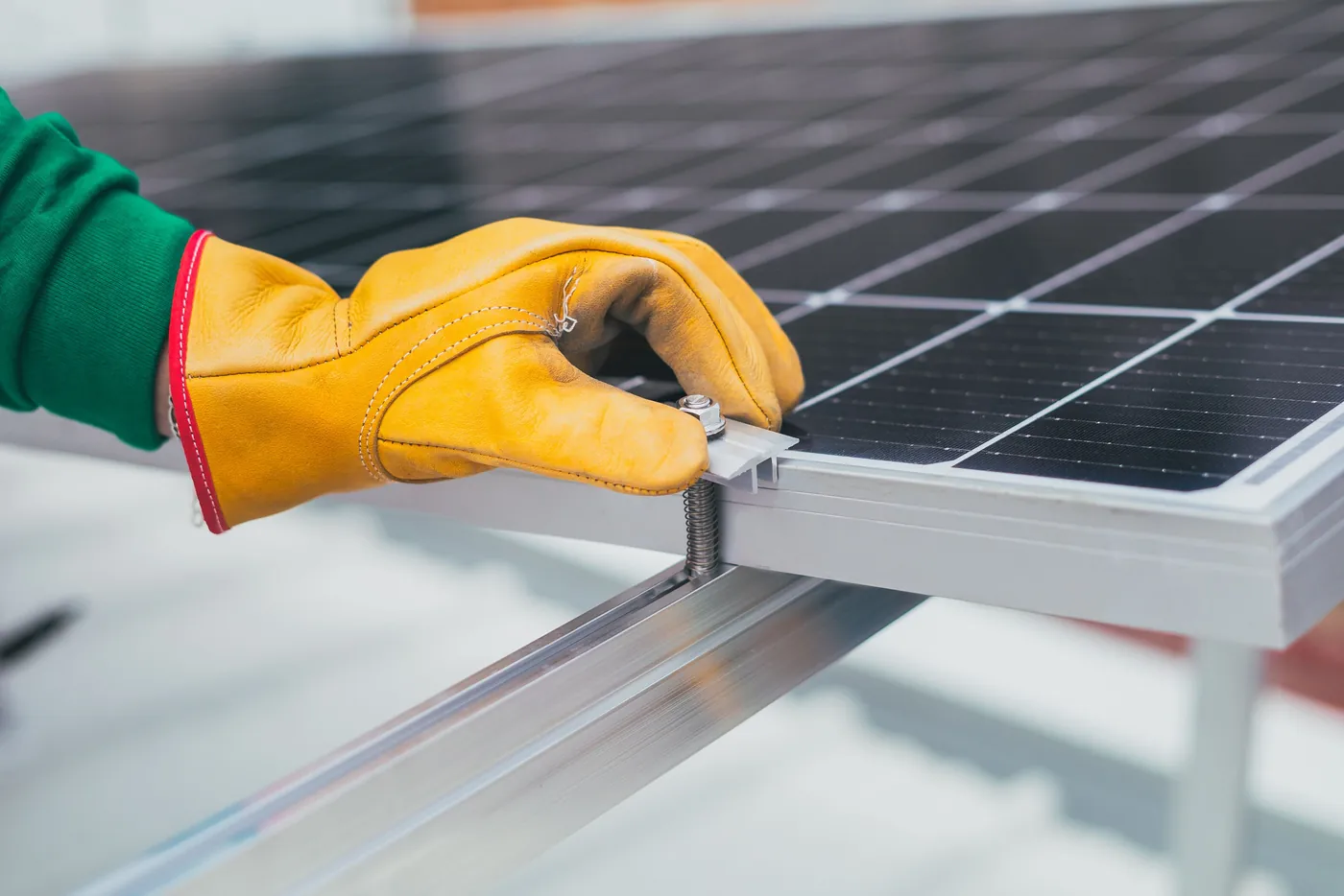Hand im Arbeitshandschuh setzt eine Modulklemme auf die Montageschiene (Zörnigall, Landkreis Wittenberg)
