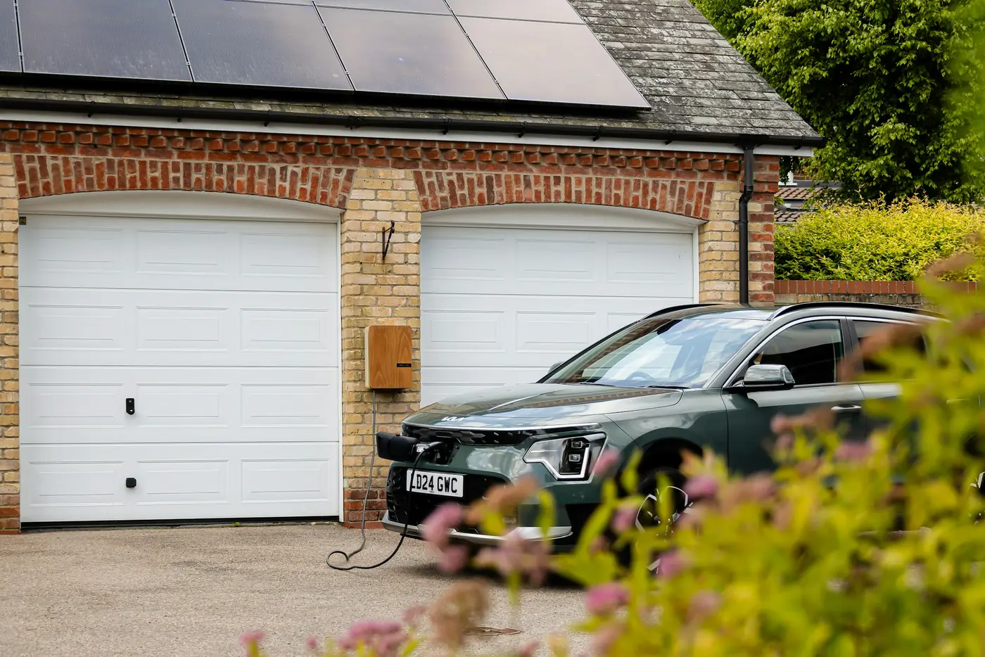 Elektroauto lädt an einer Wallbox vor der Doppelgarage, Solarmodule auf dem Dach (Vorst, Rhein-Kreis Neuss)